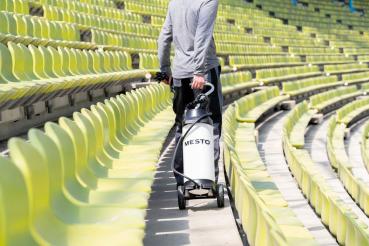 Anwendung des MESTO CLEANER F10 Drucksprühgeräts im Stadion – rückwärtige Ansicht mit Transport auf Rollen.