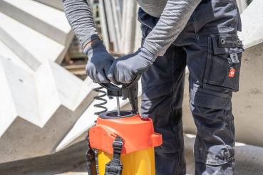 Bediener pumpt das MESTO FERROX PLUS 10 Hochdrucksprühgerät 3565F auf Baustelle mit Betonfertigteilen auf