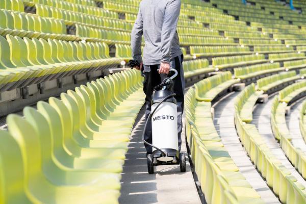 Anwendung des MESTO CLEANER F10 Drucksprühgeräts im Stadion – rückwärtige Ansicht mit Transport auf Rollen.